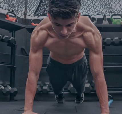 A muscular young man doing push ups in a modern gym setting