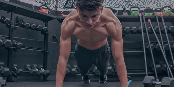 A muscular young man doing push ups in a modern gym setting